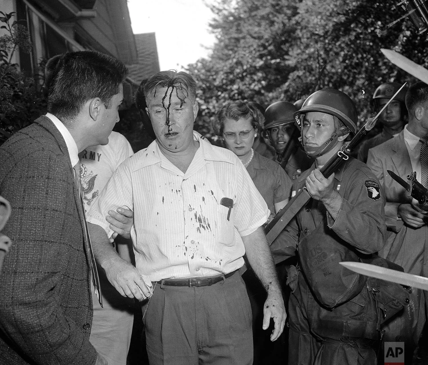 In this Sept. 25, 1957 photo, a U.S. Army paratrooper uses the butt of his rifle to nudge along a man identified as C.E. Blake, who was hit in the head when he tried to take a weapon from a trooper near Central High School in Little Rock, Ark., where integration is being enforced by the Army. (AP Photo)