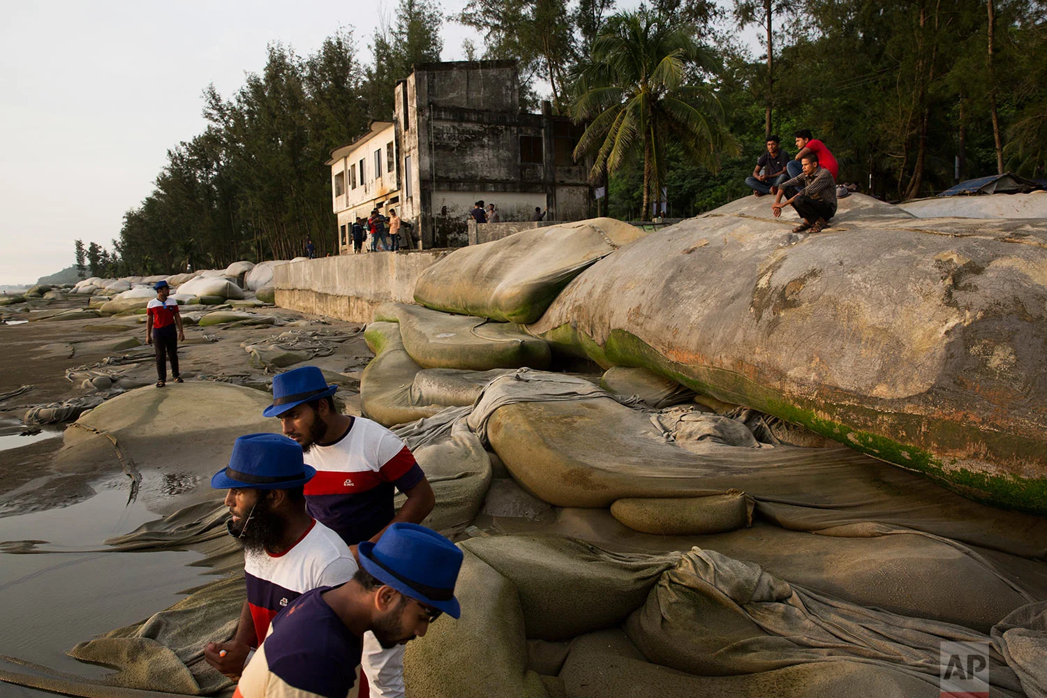 In this Saturday, Sept. 23, 2017 photo, Bangladeshi men sit on an embankment and watch the sun set at a beach in Cox's Bazar area, Bangladesh. (AP Photo/Bernat Armangue)