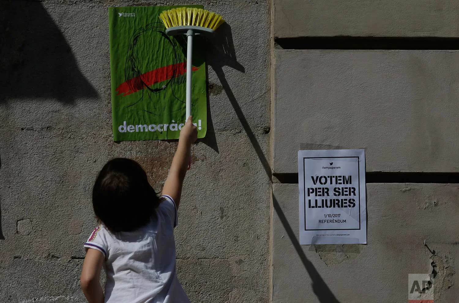 A girl pastes a banner on a wall calling for voting on a planned independence referendum in Barcelona, Spain, Sunday, Sept. 24, 2017. (AP Photo/Manu Fernandez)
