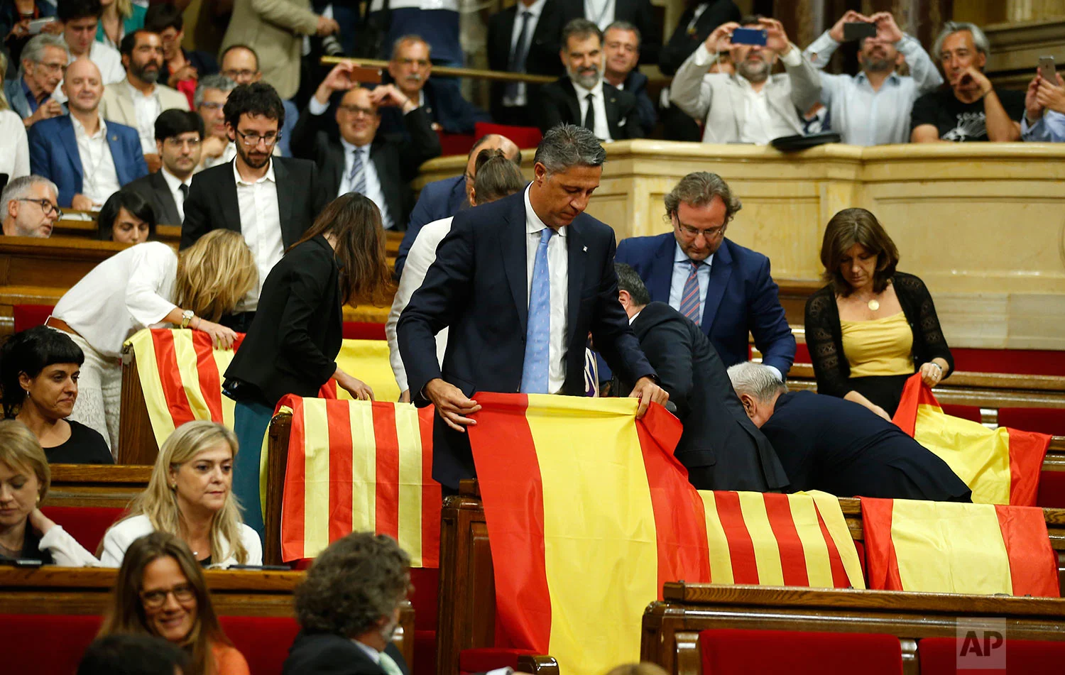 Members of the Catalan Popular Party display Spanish flags just before abandoning the session ahead of the voting during a plenary session at the Parliament of Catalonia in Barcelona, Spain, Wednesday, Sept. 6, 2017. Catalan lawmakers are voting on a bill that will allow regional authorities to officially call an Oct. 1 referendum on a split from Spain, making concrete a years-long defiance of central authorities, who see the vote as illegal. (AP Photo/Manu Fernandez)