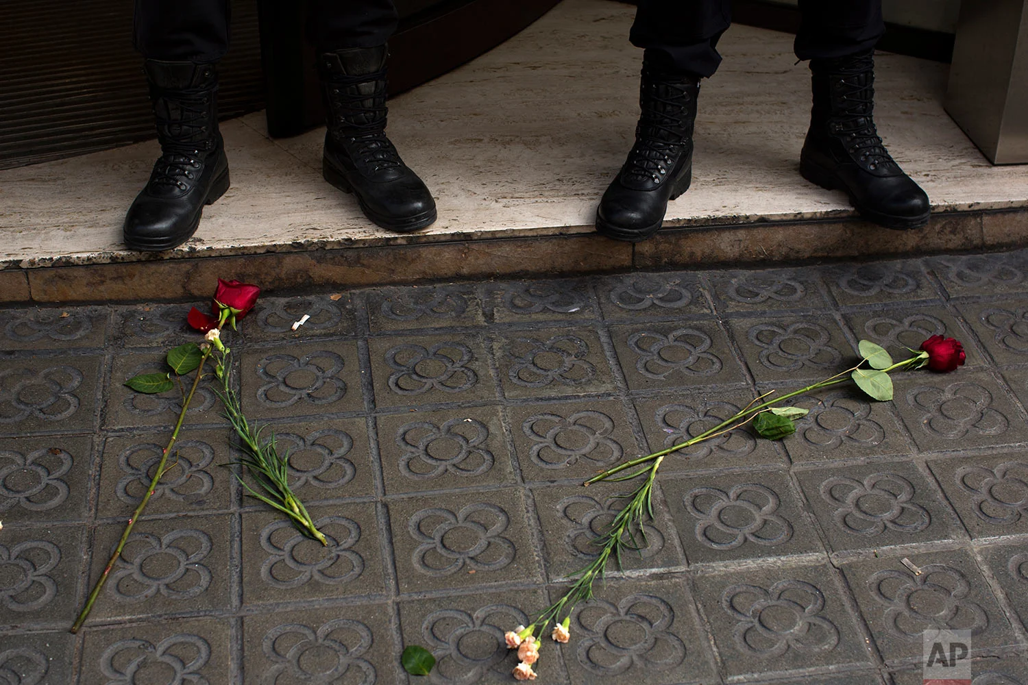 Guardia Civil officers stand guard next to flowers dropped by pro-independence demonstrators outside the headquarters of the region's department of External Affairs in Barcelona, Spain, Wednesday, Sept. 20, 2017. Spanish police arrested 12 people Wednesday in raids on offices of the regional government of Catalonia, news reports said, intensifying a crackdown on the region's preparations for a secession vote that Spain says is illegal. (AP Photo/Emilio Morenatti)
