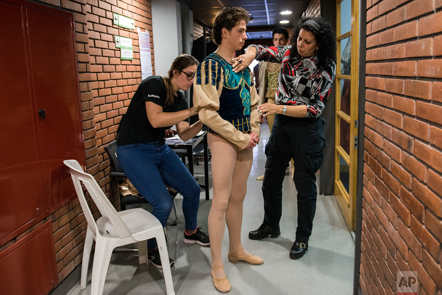  In this Tuesday, Sept. 19, 2017 photo, principal dancer Ciro Tamayo is helped by costume assistants before a dress rehearsal of Romeo and Juliet in Montevideo, Uruguay.   (AP Photo/Matilde Campodonico) 