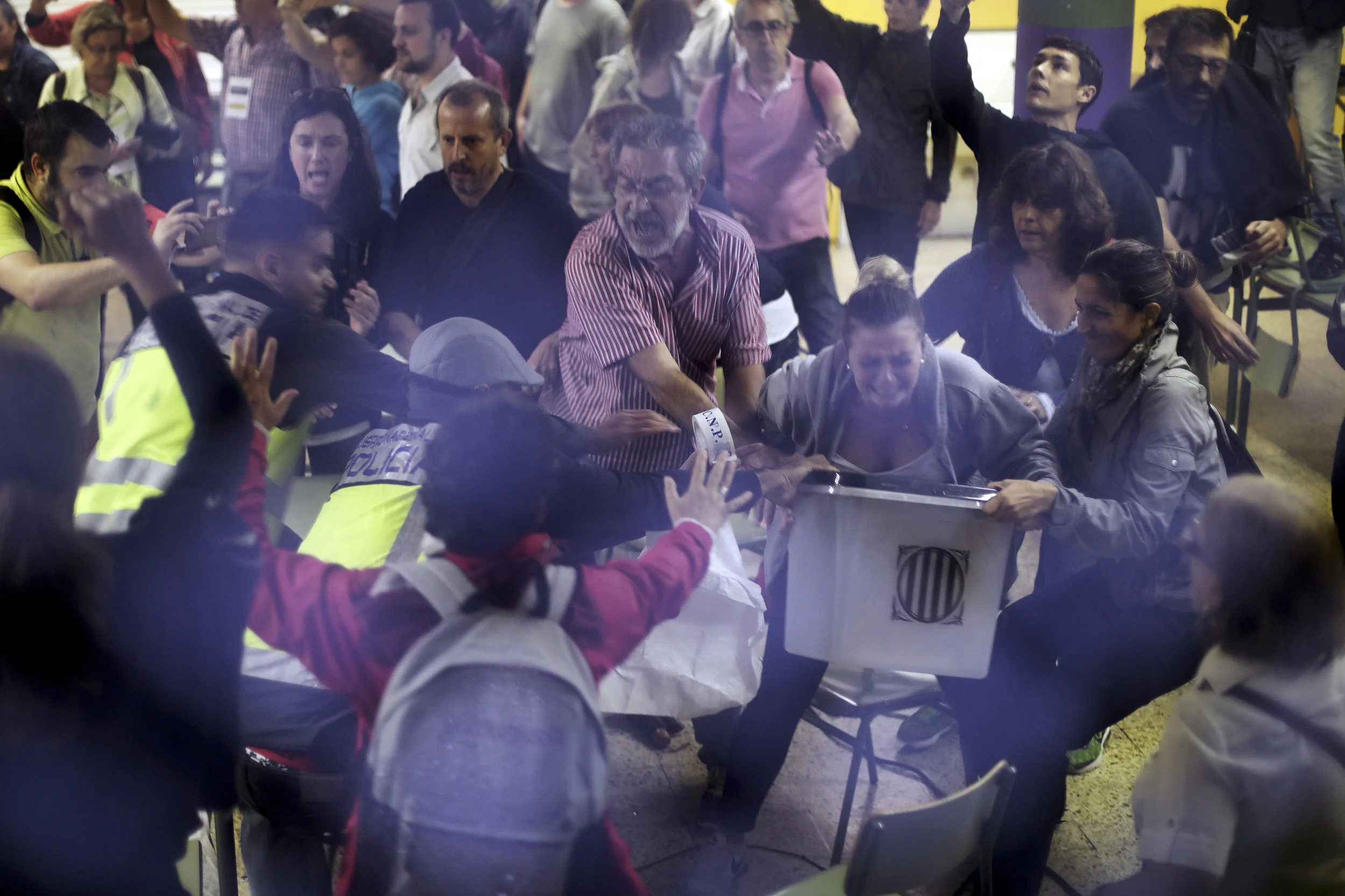 Spanish National Police officers in plain clothes try to snatch a ballot box from polling station officials at the Ramon Llull school assigned to be a polling station by the Catalan government in Barcelona, Spain, early Sunday, Oct. 1, 2017. (AP Photo/Manu Brabo)