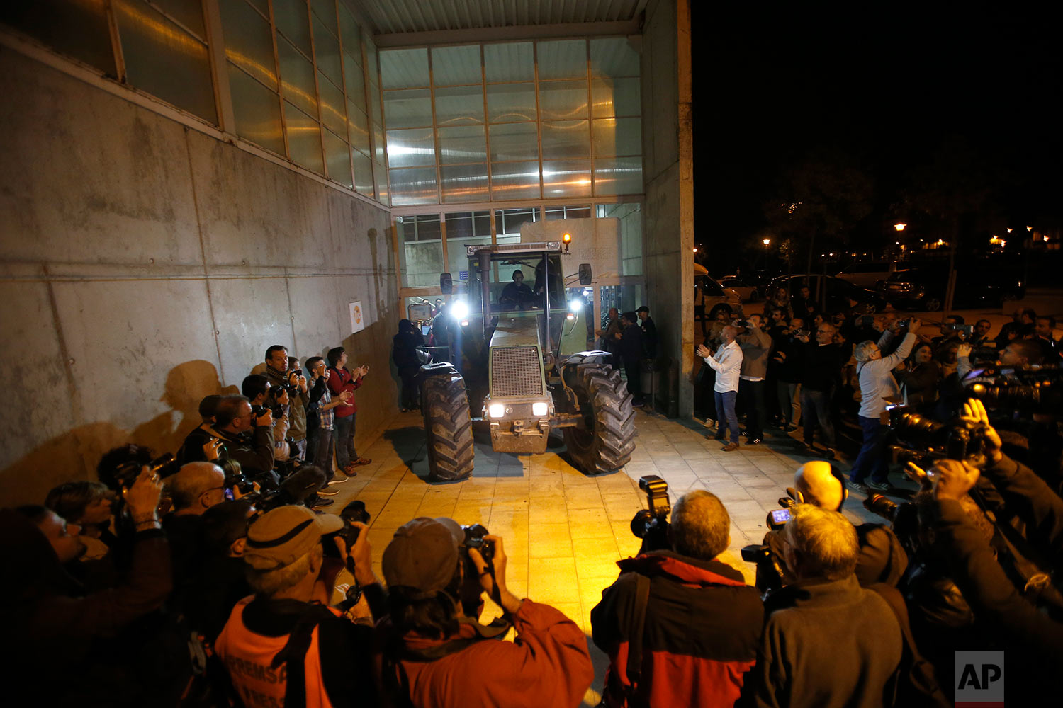  As journalists take pictures, a parked tractor blocks the door of a sports center, assigned to be a polling station by the Catalan government and where Catalan President Carles Puigdemont is expected to vote, in Sant Julia de Ramis, near Girona, Spa