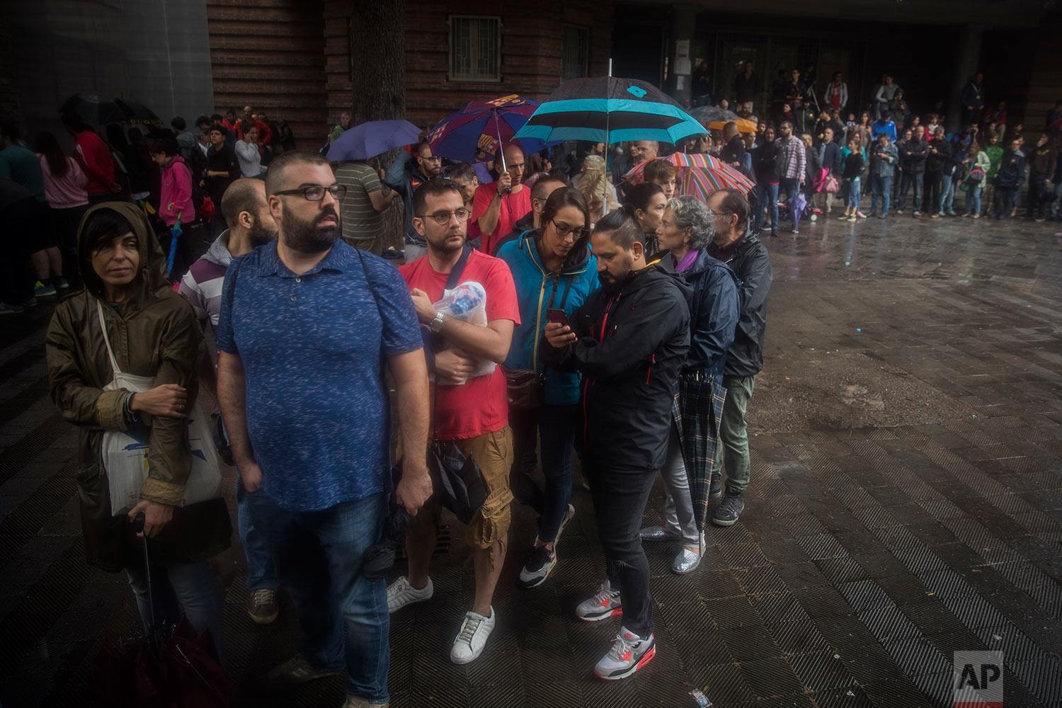  People queue to vote at a school listed to be a polling station by the Catalan government in Barcelona, Spain, Sunday, Oct. 1, 2017. Polling has begun in a banned referendum on Catalonia's independence, with the first voters casting ballots. Spanish