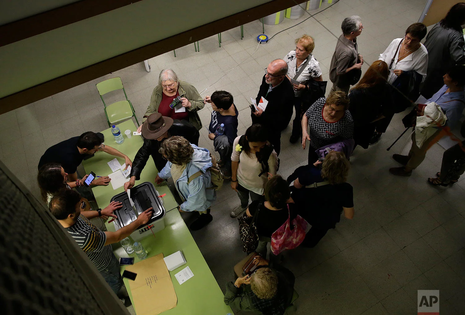 People vote at the Escola de la Concepcio, a school assigned to be a polling station by the Catalan government, in Barcelona Sunday, Oct. 1 2017. The Spanish government and its security forces are trying to prevent voting in the independence referendum, which is backed by Catalan regional authorities. Spanish officials had said force wouldn't be used, but that voting wouldn't be allowed. (AP Photo/Manu Fernandez)