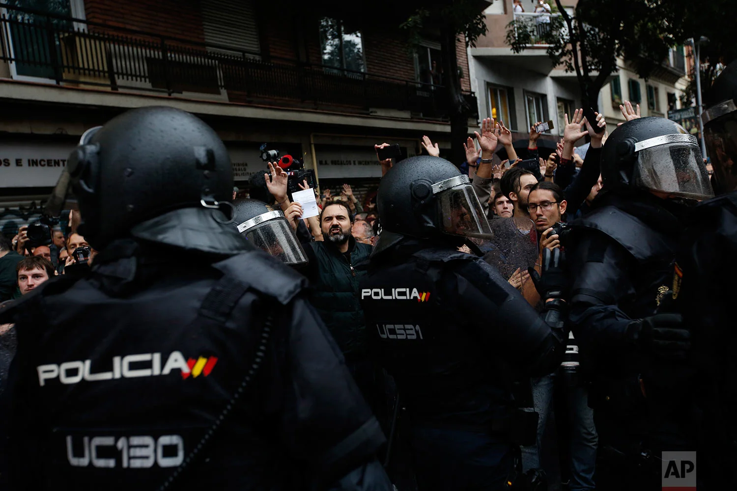 A man shows a ballot paper as Spanish National Police blocks people from approaching the Ramon Llull school assigned to be a polling station by the Catalan government in Barcelona, Spain, early Sunday, 1 Oct. 2017. Catalan pro-referendum supporters vowed to ignore a police ultimatum to leave the schools they are occupying to use in a vote seeking independence from Spain. (AP Photo/Emilio Morenatti)