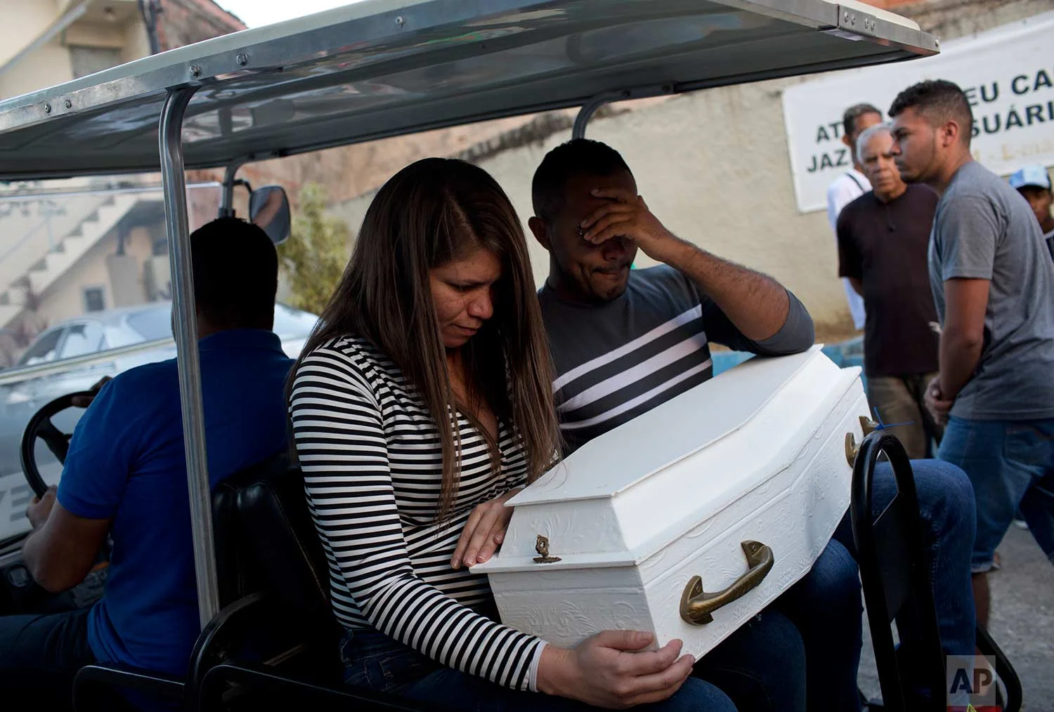 In this July 31, 2017 photo, Claudineia dos Santos Melo and her husband Klebson Cosme da Silva, hold the coffin containing the remains of their newborn son Arthur, as they transported to the crypt, at a cemetery in Rio de Janeiro, Brazil. Melo was almost nine months pregnant when she was caught in the crossfire between police and drug traffickers. Doctors performed a cesarean and discovered that a bullet had also hit her baby, damaging his lungs and spine. (AP Photo/Silvia Izquierdo, File)