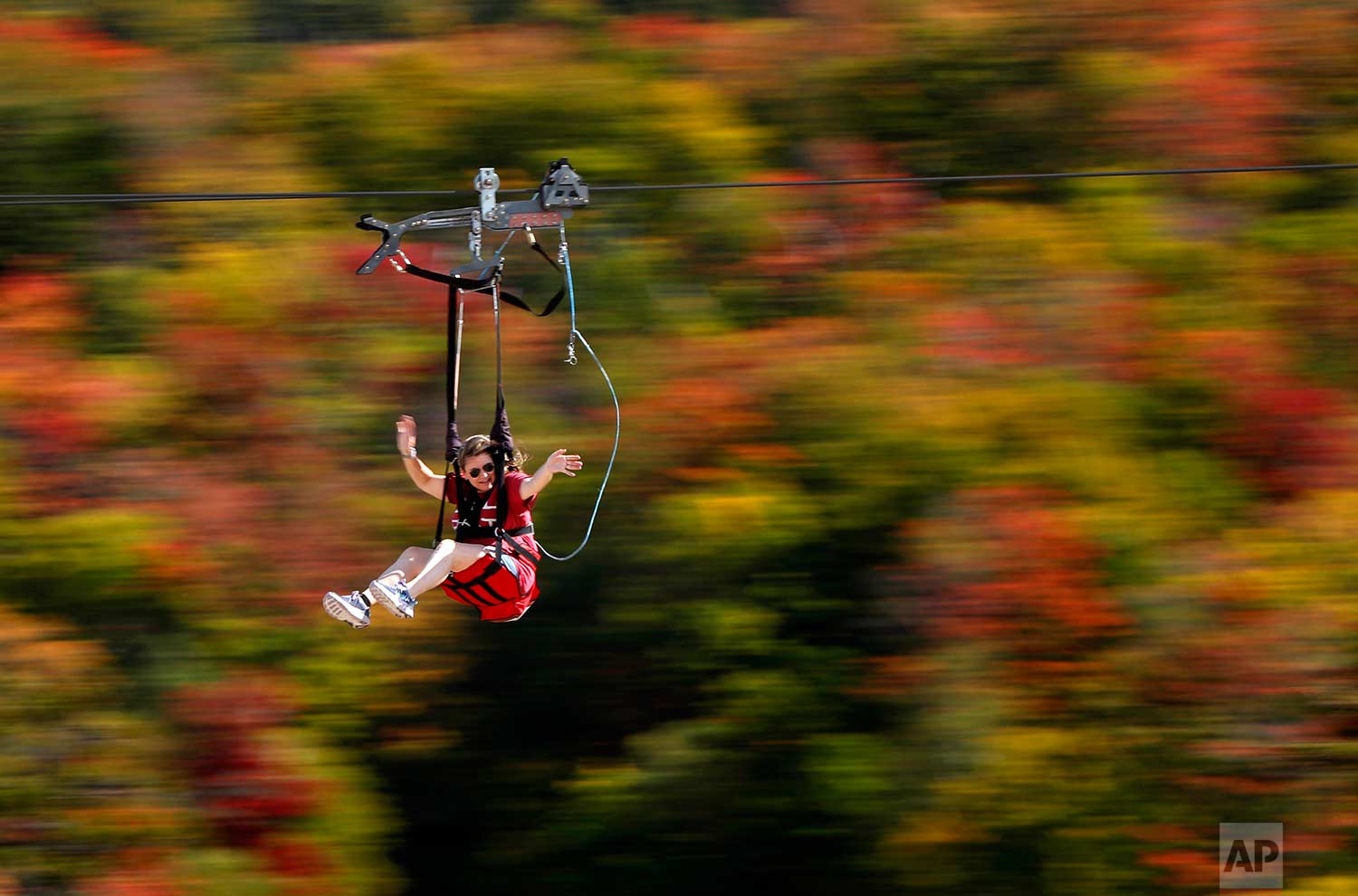  Katie McWalter of Southborough, Mass., sails by the fall foliage while riding the ZipRider at Wildcat Mountain, Saturday, Sept. 23, 2017, in Pinkham Notch, N.H. The first weekend of autumn is unusually warm with temperatures climbing into the upper 