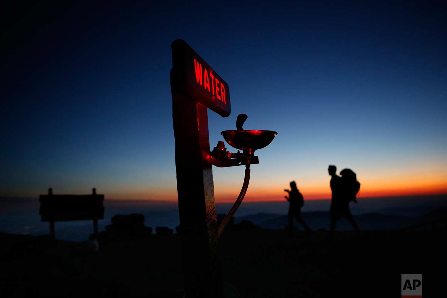  In this Sunday, Sept. 24, 2017 photo, Quincy Andrews, left, and Josh Fournier, both of Meredith, N.H., arrive at dawn at the summit of Mount Washington, N.H., where a water fountain awaits visitors to New England's highest peak. The weather observat