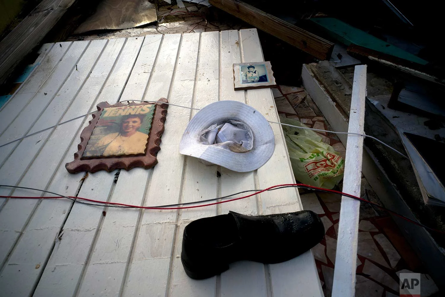 Two portraits, a hat and a shoe belonging to Luis Cosme litter a wall of his downed house destroyed by Hurricane Maria in the San Lorenzo neighborhood of Morovis, Puerto Rico, Sunday, Oct. 1, 2017. (AP Photo/Ramon Espinosa)