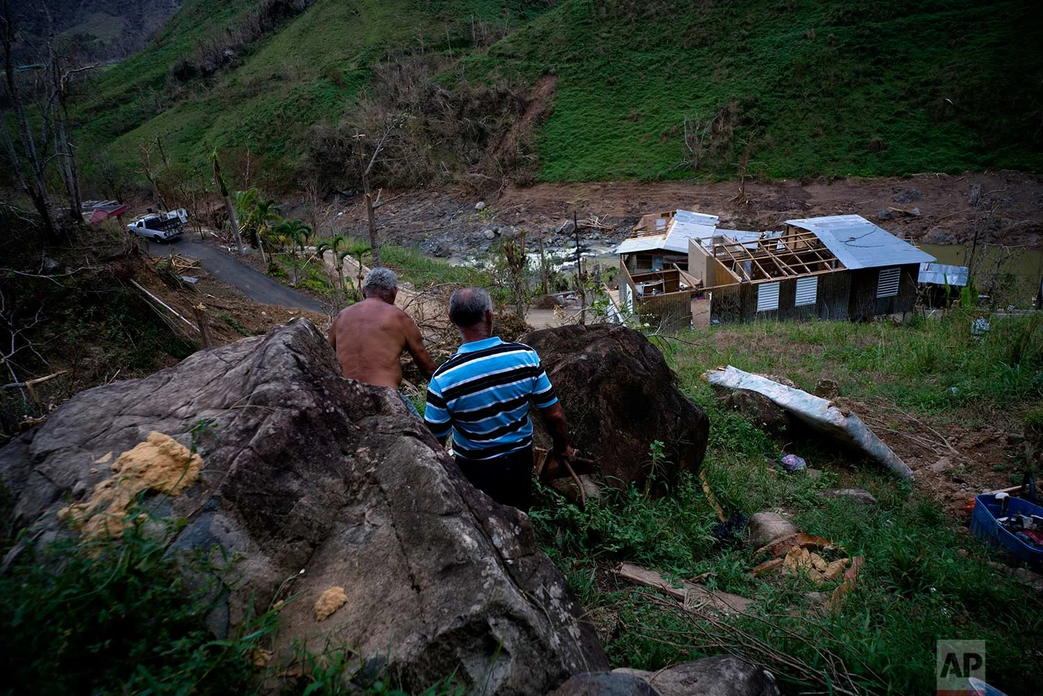 Salvador Sortre Vazquez , center, and his brother Angel Luis walk on the mountain in the direction of what is left of their house destroyed by Hurricane Maria, in Morovis, Puerto Rico, Sunday, Oct. 1, 2017. (AP Photo / Ramon Espinosa)