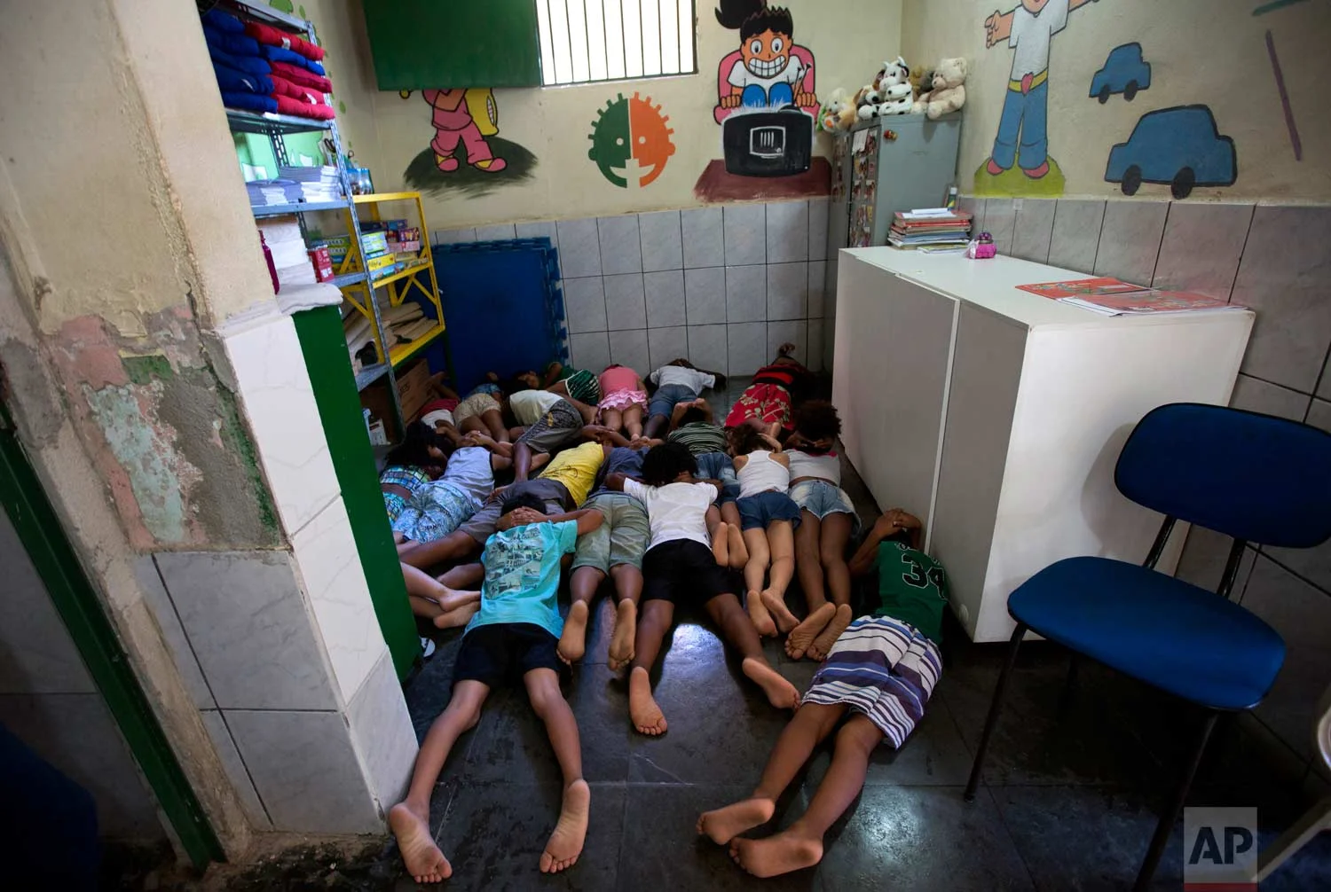In this April 5, 2017 photo, students practice taking cover during shootings between gangsters and police, in a classroom at the Uere Special Needs School, in the Mare slum in Rio de Janeiro, Brazil. With rival drug dealers on practically every corner and a militarized campaign by authorities to take them out, shootouts have become so common that the school holds drills for students to practice taking cover quickly. (AP Photo/Silvia Izquierdo)