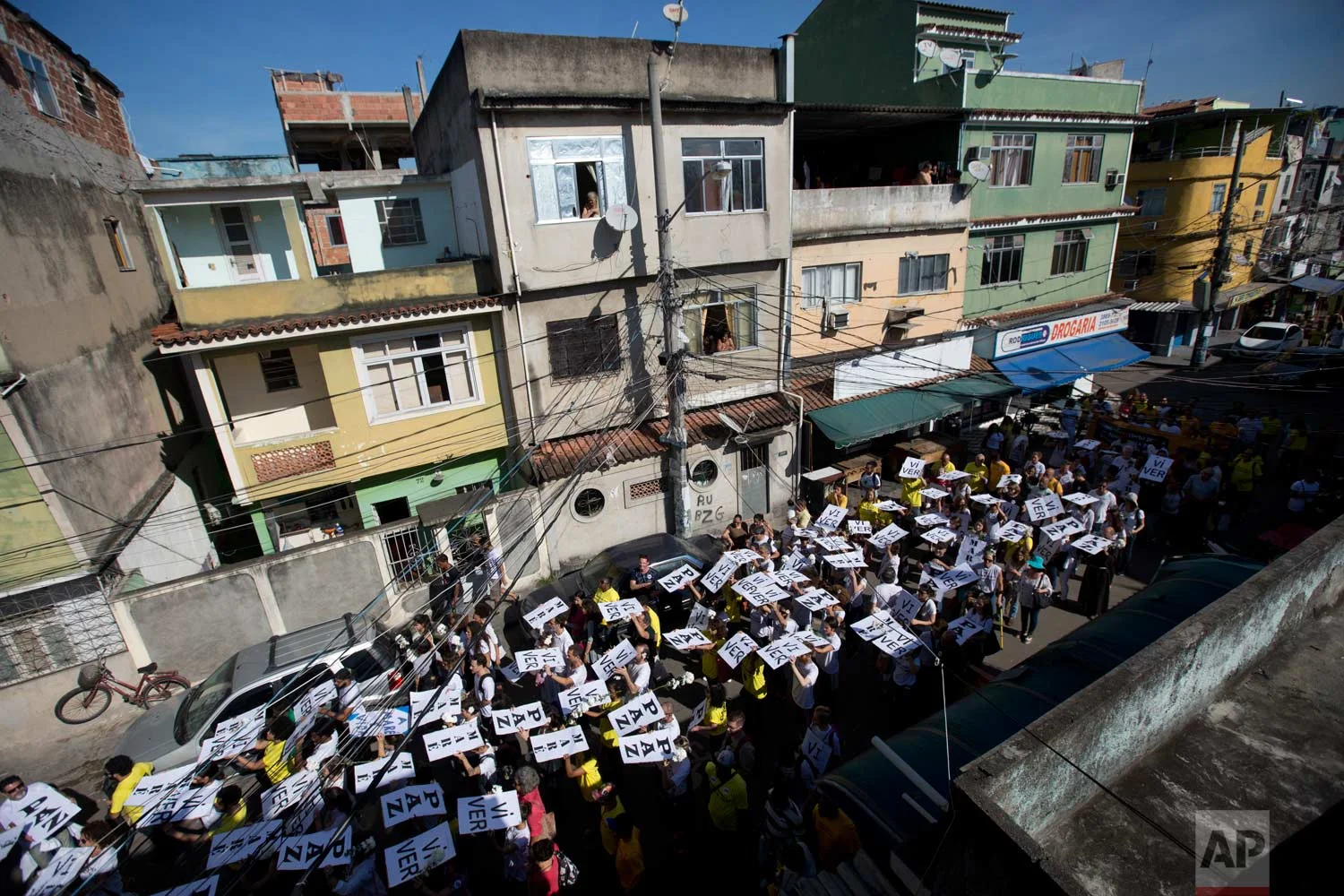 In this May 24, 2017 photo, residents and activists march demanding an end to the gun battles between police and gangs that put residents in the crossfire, in the Mare complex of slums, in Rio de Janeiro, Brazil. With an average of 15 shootings a day, gunfire is often heard across the city that hosted the Summer Olympic Games just a year ago. (AP Photo/Silvia Izquierdo)