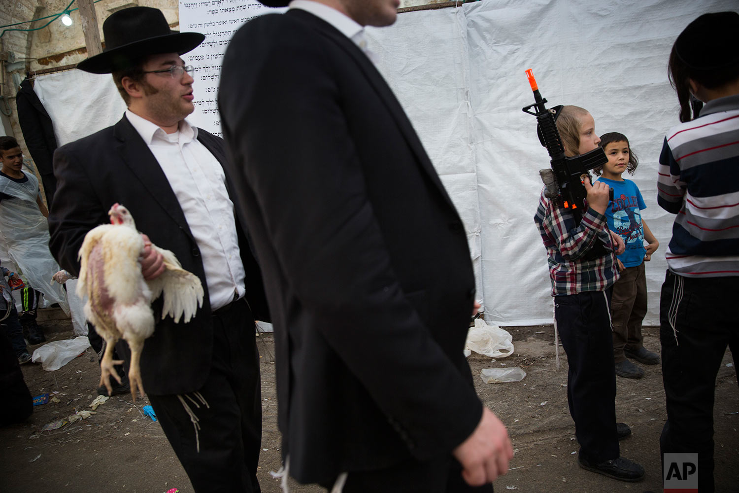  An ultra-Orthodox Jewish man holds a chicken to be used during the Kaparot ritual, as a child holds a toy gun, in Jerusalem, Wednesday, Sept. 27, 2017. (AP Photo/Oded Balilty) 