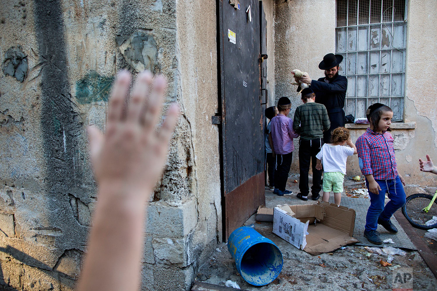  An ultra-Orthodox Jewish man swings a chicken over his children's head as part of the Kaparot ritual in Bnei Brak, Israel, Thursday, Sept. 28, 2017. (AP Photo/Oded Balilty) 