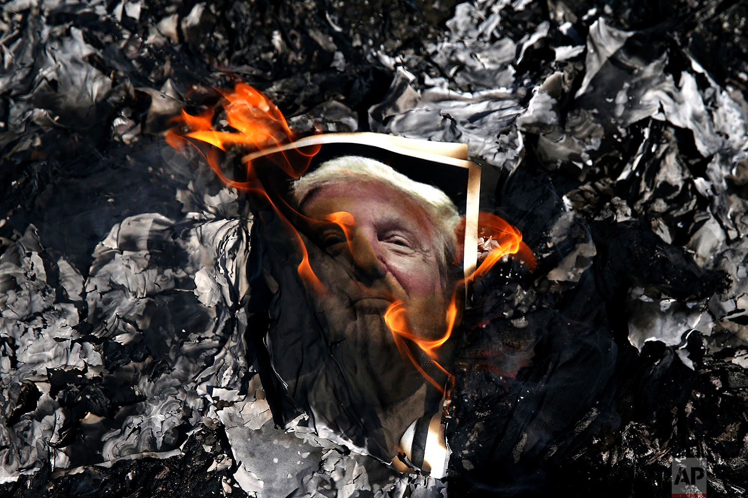 A portrait of U.S. President Donald Trump is set on fire by Iranian mourners during the state funeral of Mohsen Hojaji, a young Revolutionary Guard soldier beheaded by the Islamic State group in Syria, Wednesday, Sept. 27, 2017, in Tehran, Iran. (AP Photo/Ebrahim Noroozi)