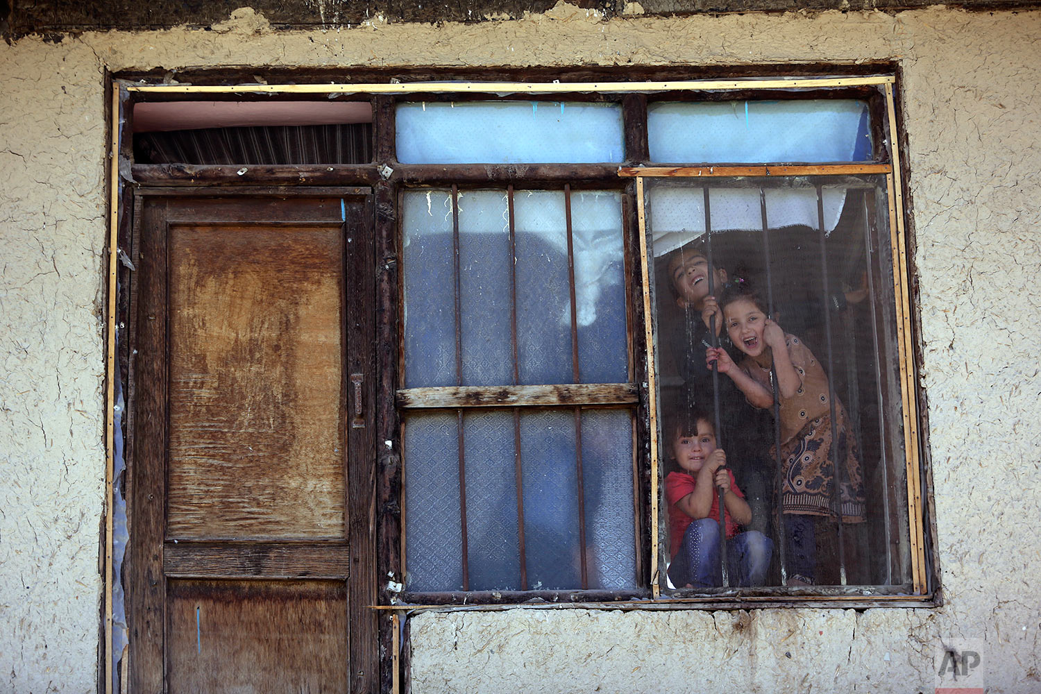  Afghan children look outside through the window of their home as they poses for photograph in the old part of Kabul, Afghanistan, Tuesday, Sept. 26, 2017. (AP Photo/Rahmat Gul) 