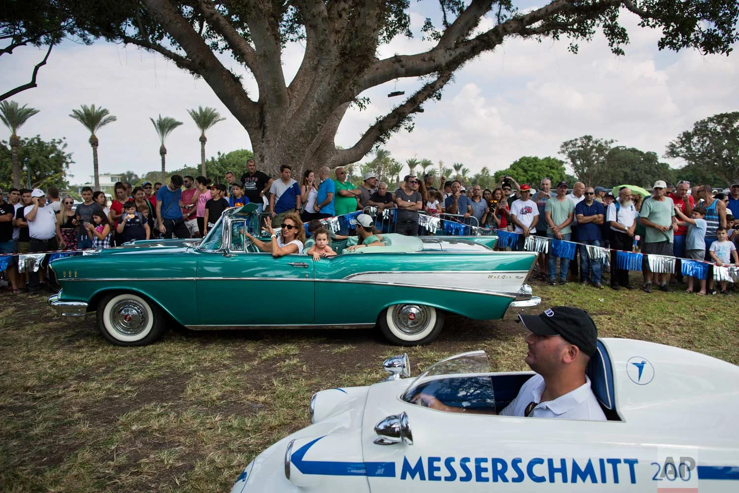 Spectators looks at 1957 Chevy Bel Air and 1957 Messerschmitt during the 31st annual "Five Club" car collectors' meeting in Ramat Gan, Israel, Friday, Oct. 6, 2017. (AP Photo/Oded Balilty)