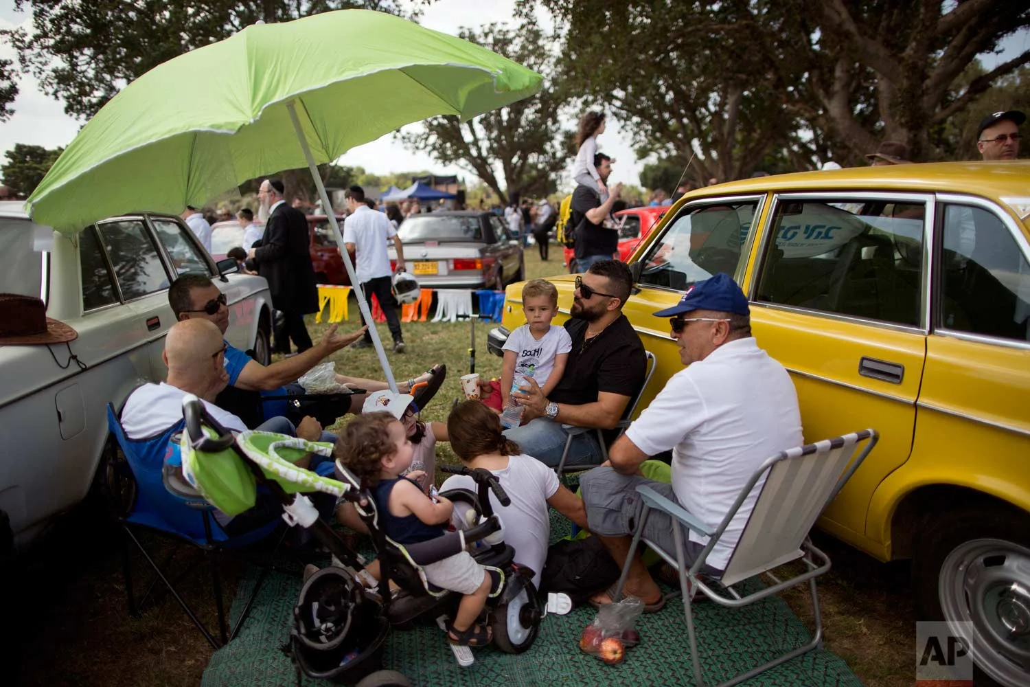 People sits next to their antique cars during the 31st annual "Five Club" collectors car meeting in Ramat Gan, Israel, Friday, Oct. 6, 2017. (AP Photo/Oded Balilty)