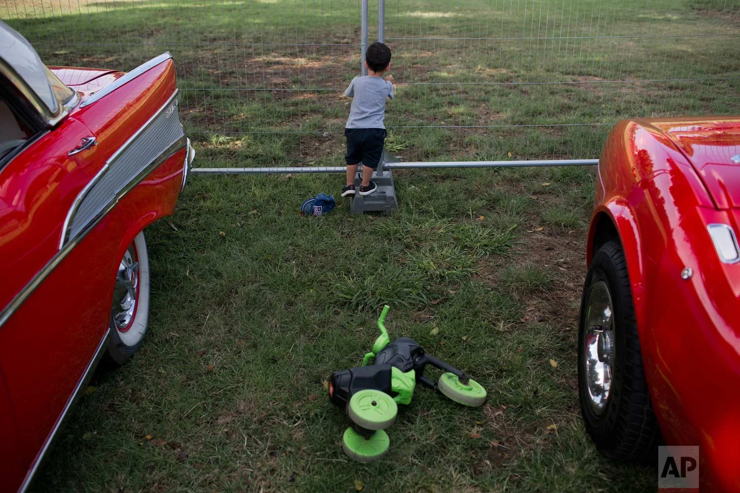 A boy looks through a fence during the 31st annual "Five Club" car collectors' meeting in Ramat Gan, Israel, Friday, Oct. 6, 2017. (AP Photo/Oded Balilty)
