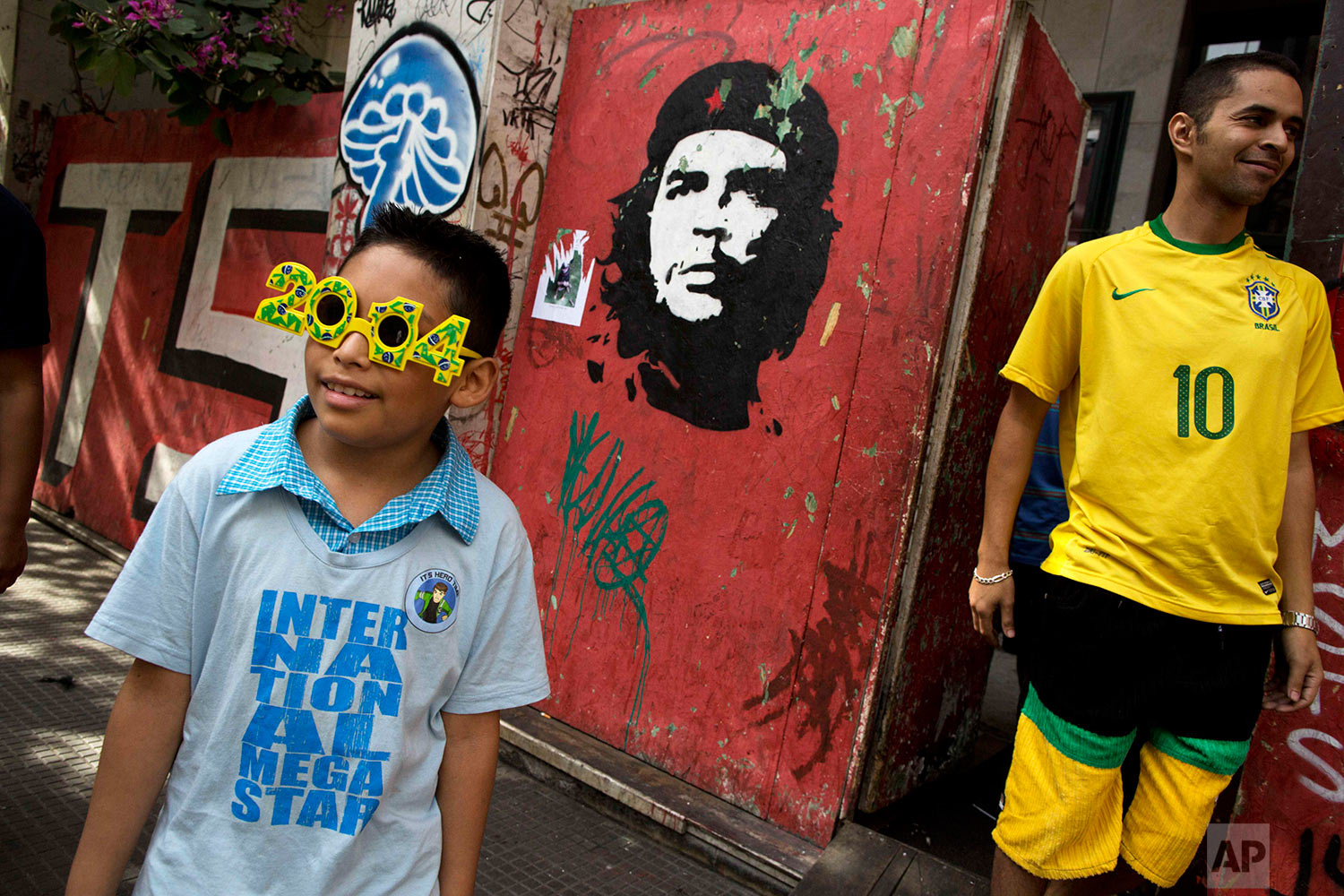  Fans of Brazil stand next to a wall painted with a portrait of famous revolutionary hero Ernesto Che Guevara before the Chile vs. Brazil match during the 2014 soccer World Cup in Sao Paulo, Brazil, Saturday, June 28, 2014.(AP Photo/Rodrigo Abd) 