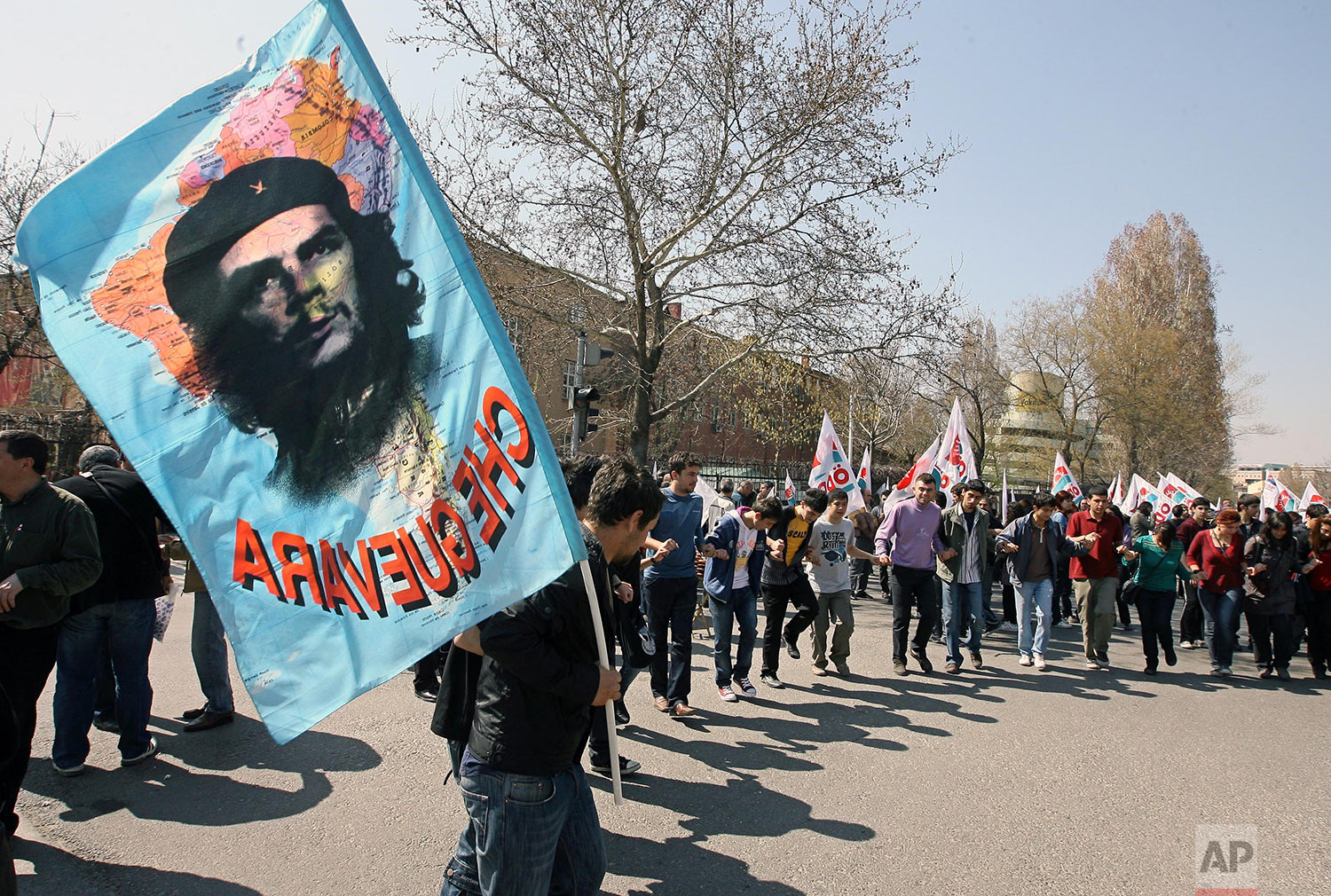  Turkish students demonstrate as one of them waves a flag with a poster of Latin American revolutionary legend Che Guevara during a protest rally against NATO and U. S. President Barack Obama, in Ankara, Turkey, Saturday, April 4, 2009. (AP Photo/Bur