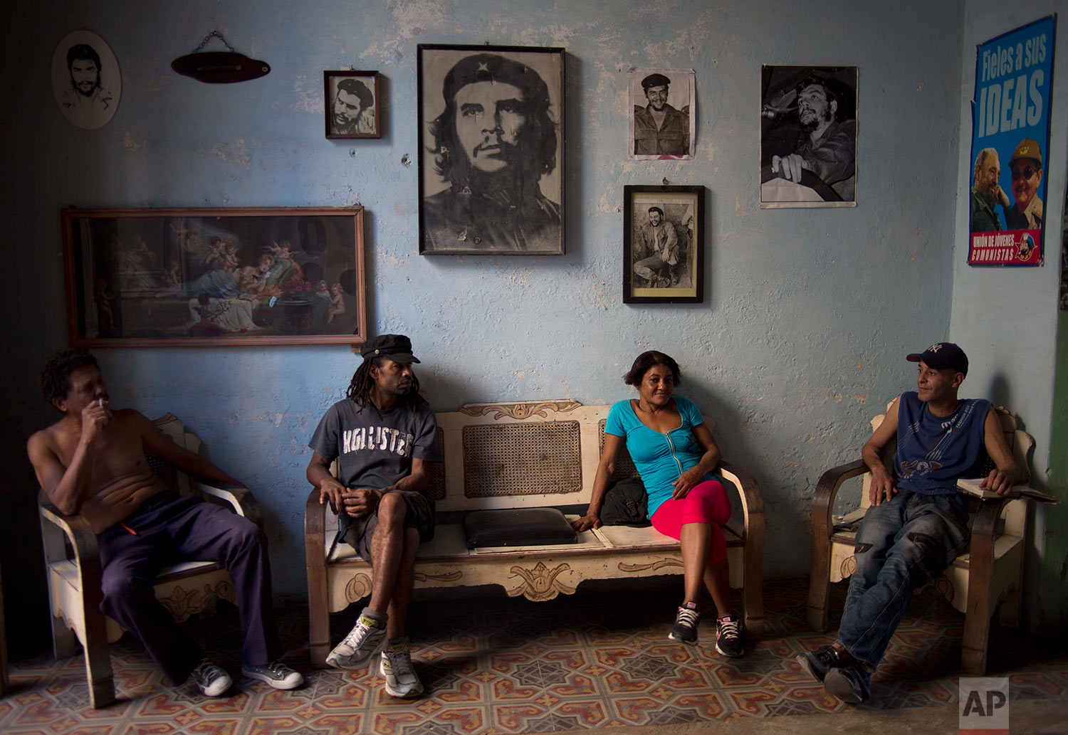  Roberto Alvarez, 47, right, chats with friends backdropped by a wall decorated with images of Cuban revolutionary heroes, Che Guevara, Fidel Castro and his brother, President Raul Castro, in Havana, Cuba, Wednesday, Feb. 25, 2015. (AP Photo/Ramon Es