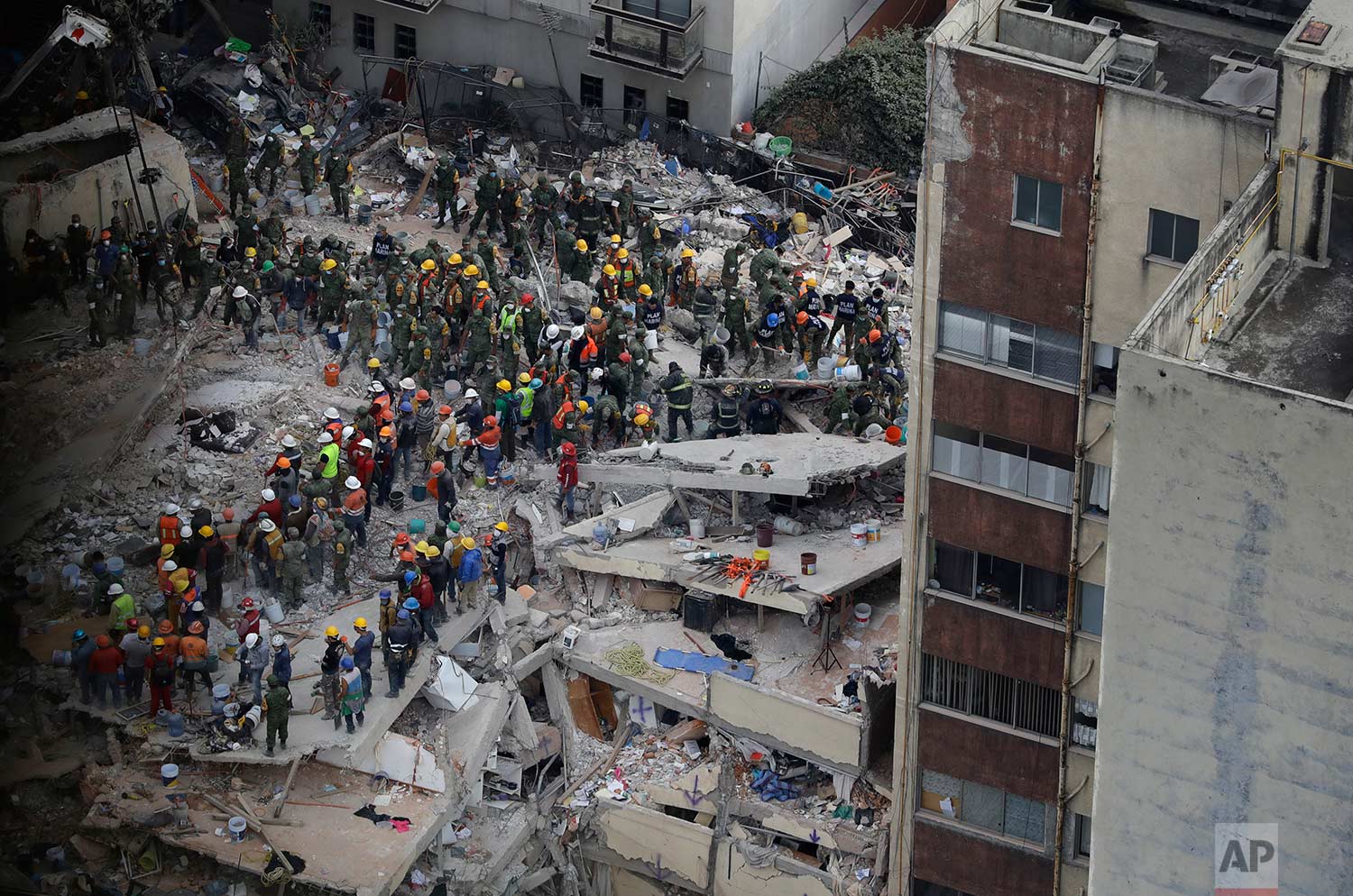 Rescue workers search for people trapped inside a collapsed building felled by a 7.1 magnitude earthquake in the Del Valle area of Mexico City, Wednesday, Sept. 20, 2017. (AP Photo/Rebecca Blackwell)