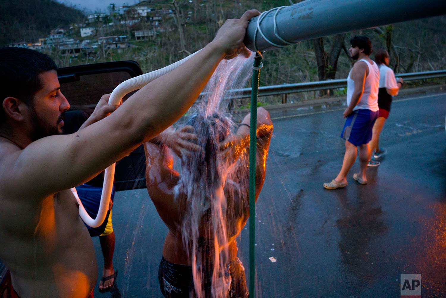 People affected by Hurricane Maria bathe in water pipes from a creek in the mountains, in Naranjito, Puerto Rico, Thursday, Sept. 28, 2017. (AP Photo/Ramon Espinosa)