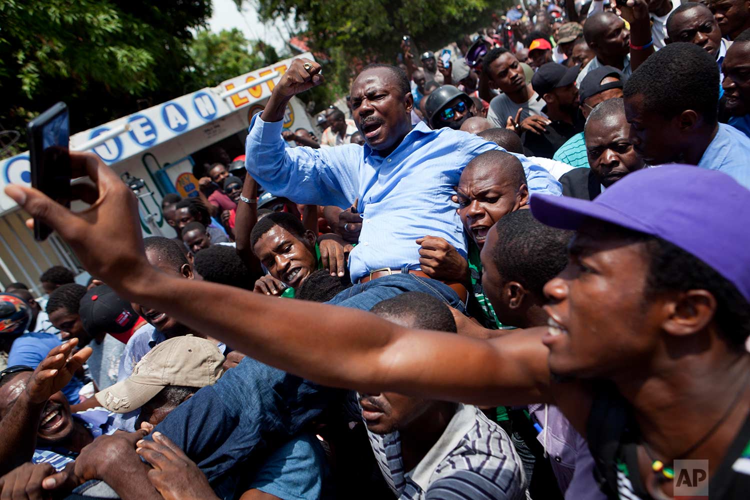 Former presidential candidate Moise Jean-Charles, from the Platform Pitit Dessalines party, is carried by supporters after national police officers attempted to detain him in Delmas, a district of Port-au-Prince, Haiti, Wednesday, Sept. 13, 2017. (AP Photo/Dieu Nalio Chery)