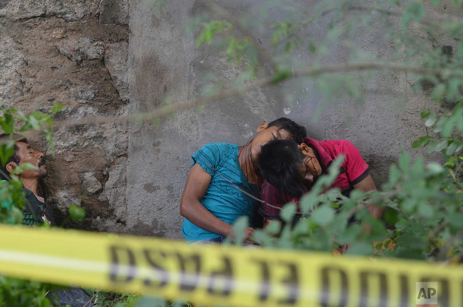 EDS NOTE: GRAPHIC CONTENT - The bodies of three men, two of them teenagers, lie against a wall under an overpass on a highway after being shot in the town of Coyuca, near Acapulco, Guerrero state, Mexico, Tuesday, Sept. 12, 2017. (AP Photo/Bernandino Hernandez)