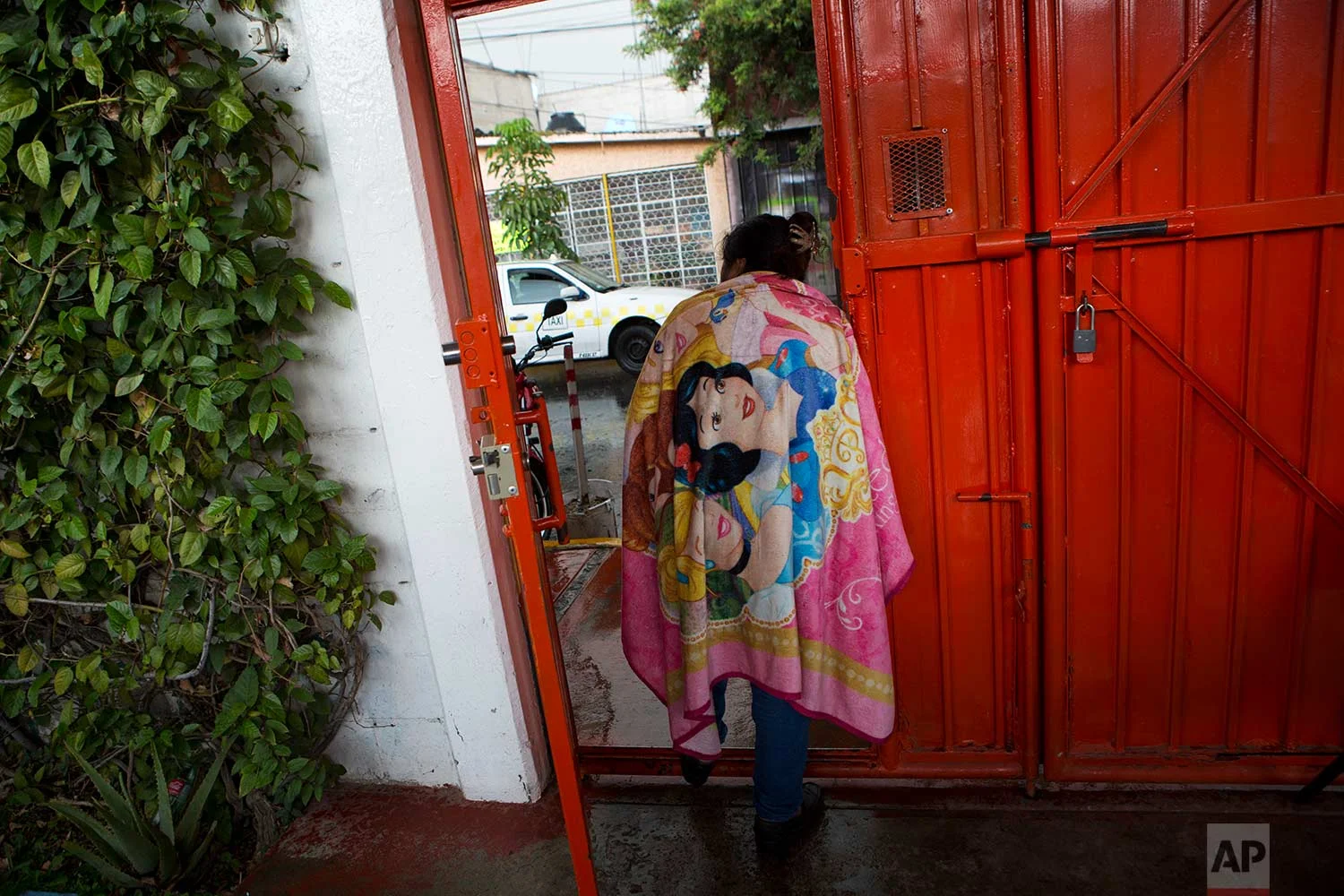 In this Aug. 25, 2017 photo, a cleaning lady looks out the door of a nursing school, monitored by a security guard, in Nezahualcoyotl, Mexico state. (AP Photo/Rebecca Blackwell)
