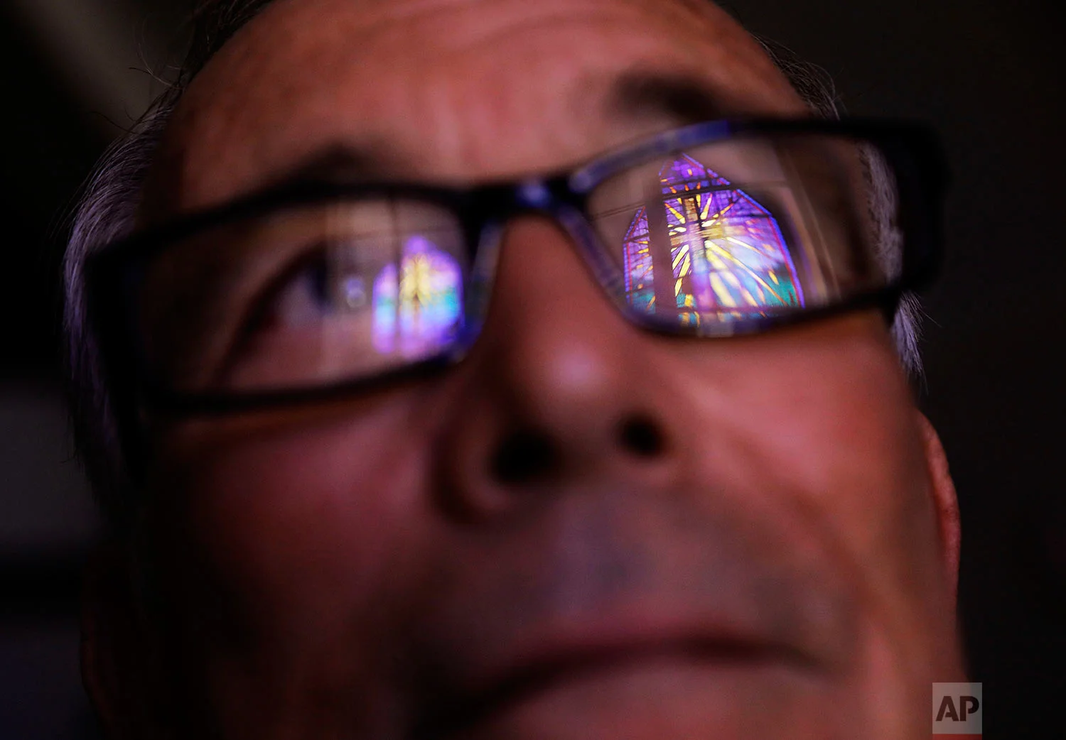 Wayne Christopher stands for a portrait in Port Arthur, Texas, Monday, Sept. 25, 2017, as a stained glass window is reflected in his glasses in the damaged sanctuary of the Memorial Baptist Church he'd attended his whole life. After the previous month's Hurricane Harvey, he said, "I think the Lord put us over the care of his creation, and when we pollute like we do, destroy the land, there's consequences to that," he said. "And it might not catch up with us just right now, but it's gonna catch up. Like a wound that needs to be healed." (AP Photo/David Goldman)
