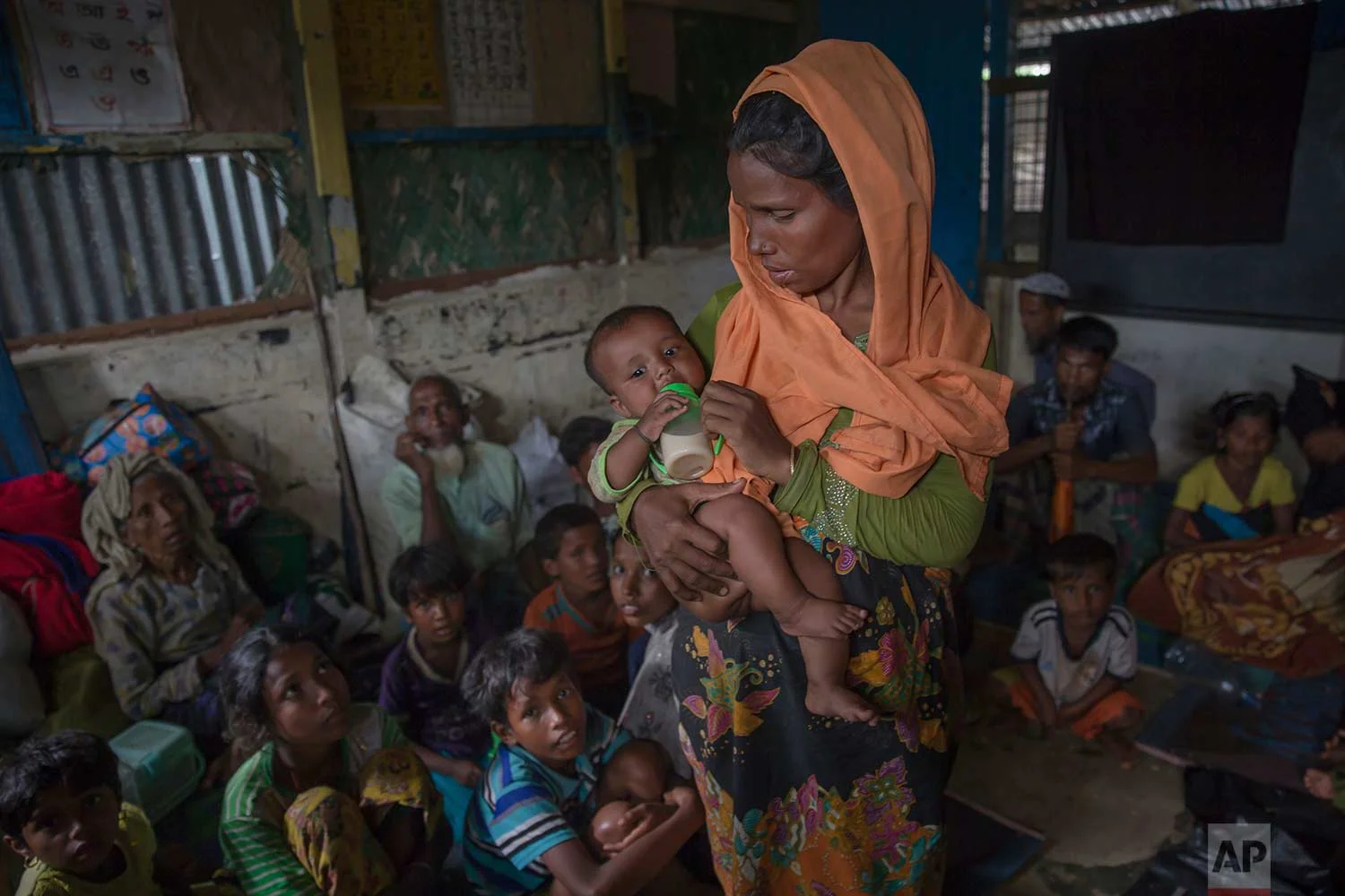 A Rohingya Muslim woman feeds her daughter inside a classroom where a group of refugees wait to be registered after which they will be allowed to proceed to build a shelter in Kutupalong refugee camp, Bangladesh, Friday, Oct. 20, 2017. (AP Photo/Dar Yasin)