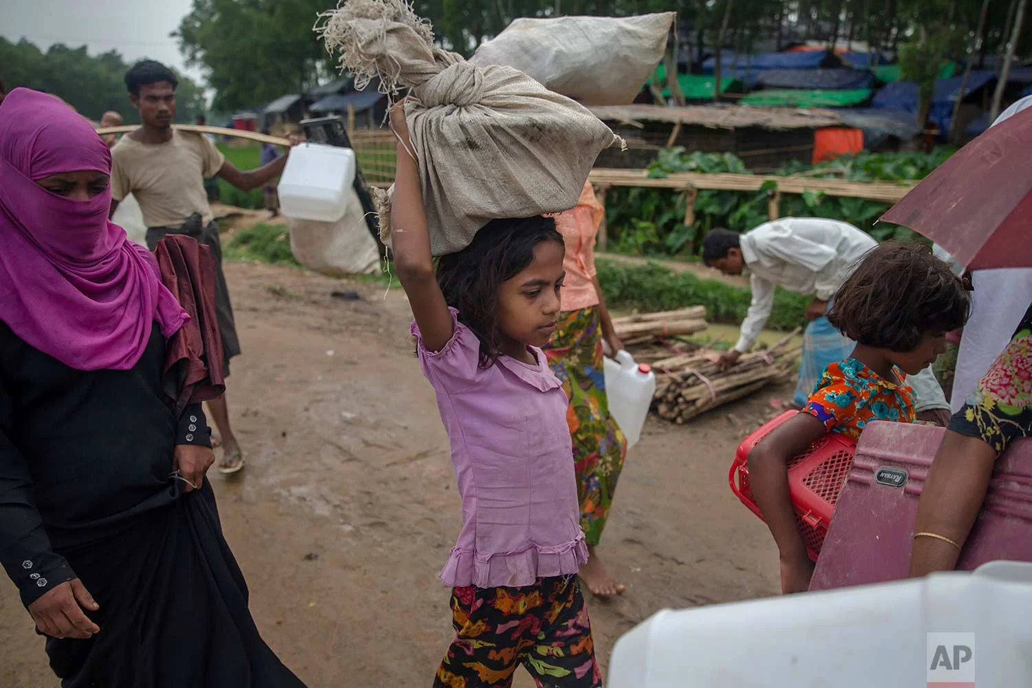A newly arrived Rohingya Muslim girl, who crossed over from Myanmar into Bangladesh, walks carrying her belongings near Kutupalong refugee camp, Bangladesh, Friday, Oct. 20, 2017. (AP Photo/Dar Yasin)