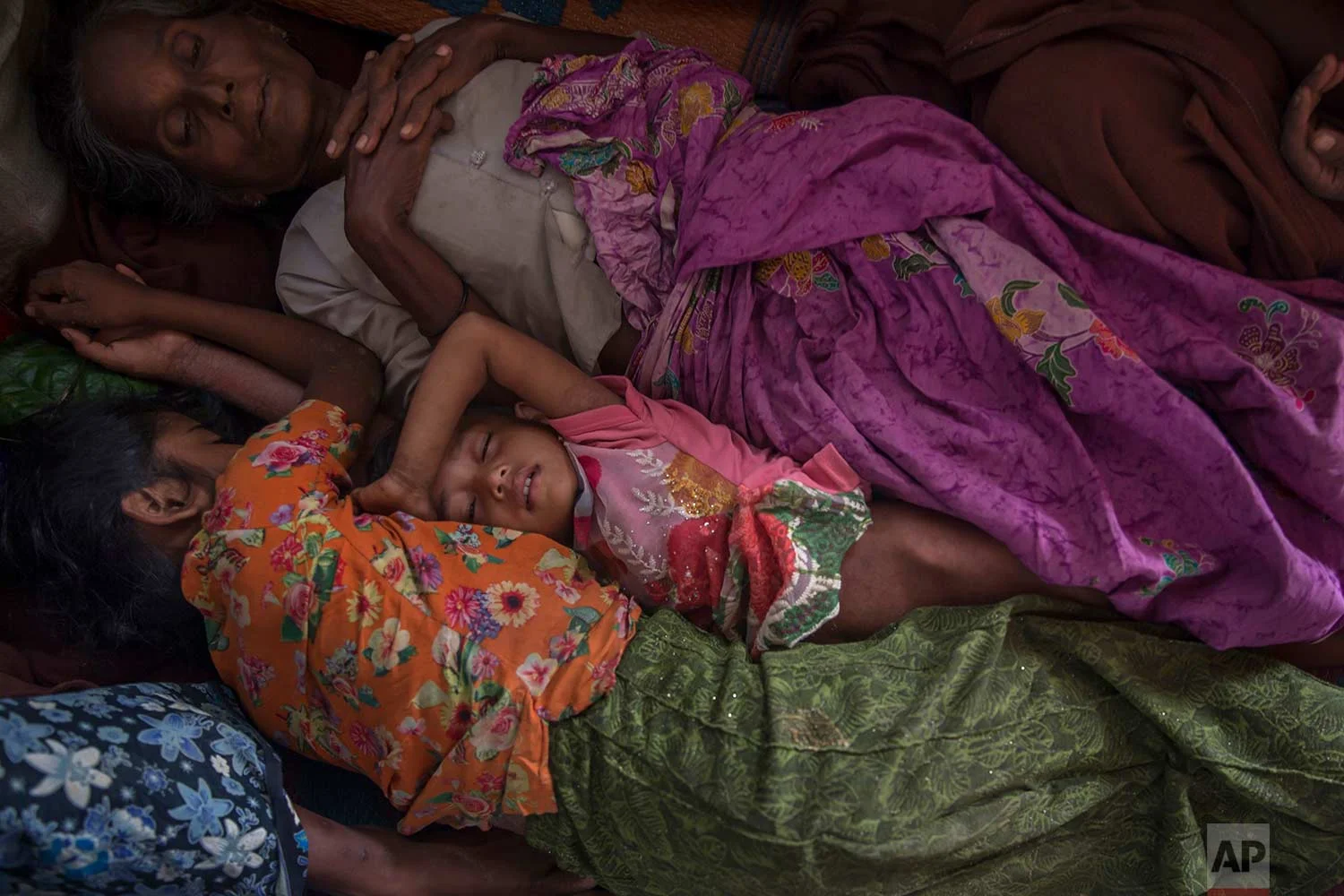 A Rohingya Muslim girl Asma Bibi, center, sleeps between her grandmother and sister in a dormitory of a school as they wait for their family to be registered as refugees after which they will be allowed to proceed to build a shelter in Kutupalong refugee camp, Bangladesh, Friday, Oct. 20, 2017.(AP Photo/Dar Yasin)