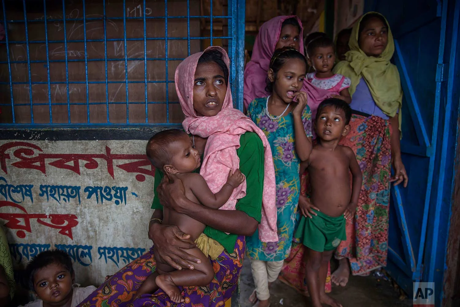 A Rohingya Muslim woman Nur Nahar, center, who crossed over from Myanmar into Bangladesh, holds her son Mohammad Junaid, as she sits in a dormitory of a school for her family to be registered as refugees after which they will be allowed to proceed to build a shelter in Kutupalong refugee camp, Bangladesh, Friday, Oct. 20, 2017. (AP Photo/Dar Yasin)