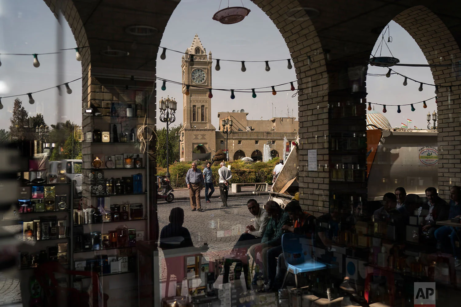People are reflected in the window of a closed shop in central Irbil, Iraq, Wednesday, Oct. 25, 2017. In Sept. 2017, Iraq's Kurds celebrated their symbolic vote for independence, but instead of moving forward with negotiations toward a smooth divorce from Baghdad, they have lost their most important oil-producing city to Iraqi troops, squeezing a hurting economy and dashing the hopes of an independent state. (AP Photo/Felipe Dana)