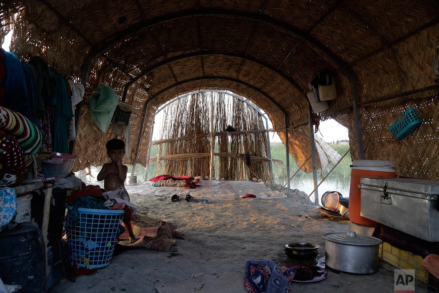 In this Sept. 10, 2017 photo, a child stands inside a traditional reed hut deep inside Iraq’s marshes in Chabaish, Iraq. While the region was declared a UNESCO heritage site in 2016 the central government in Baghdad has continued to neglect the wetlands, failing to provide basic services like electricity and schools. (AP Photo/Susannah George)