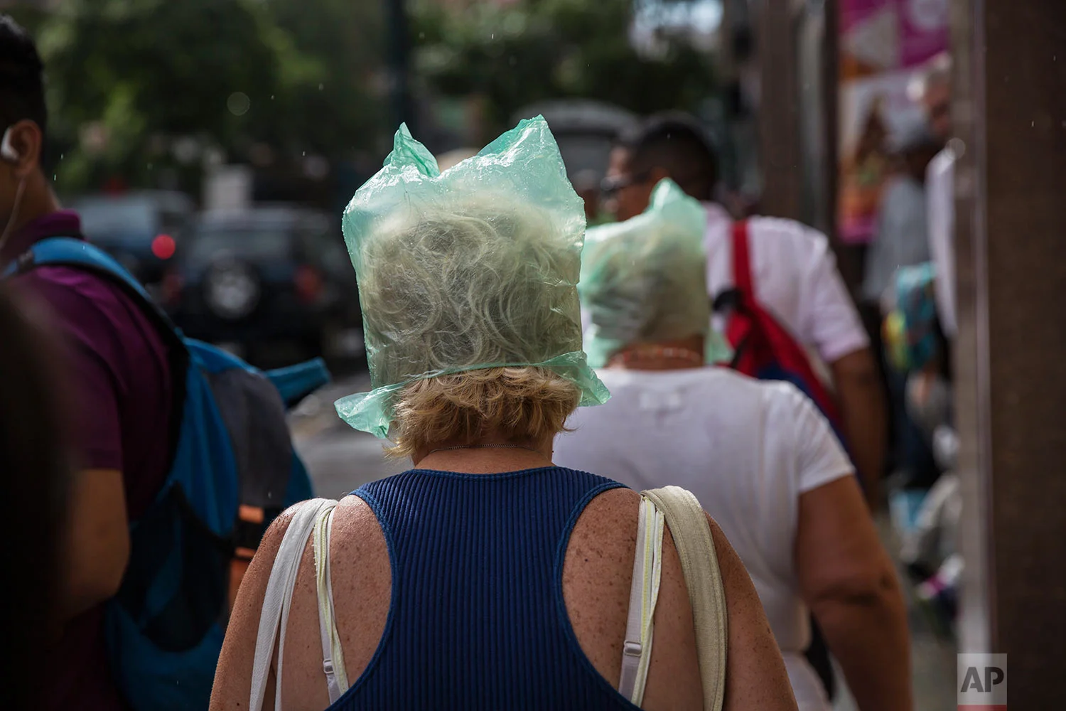 Woman keep their hair dry with plastic bags as it drizzles in downtown Caracas, Venezuela, Tuesday, Oct. 24, 2017. (AP Photo/Rodrigo Abd)