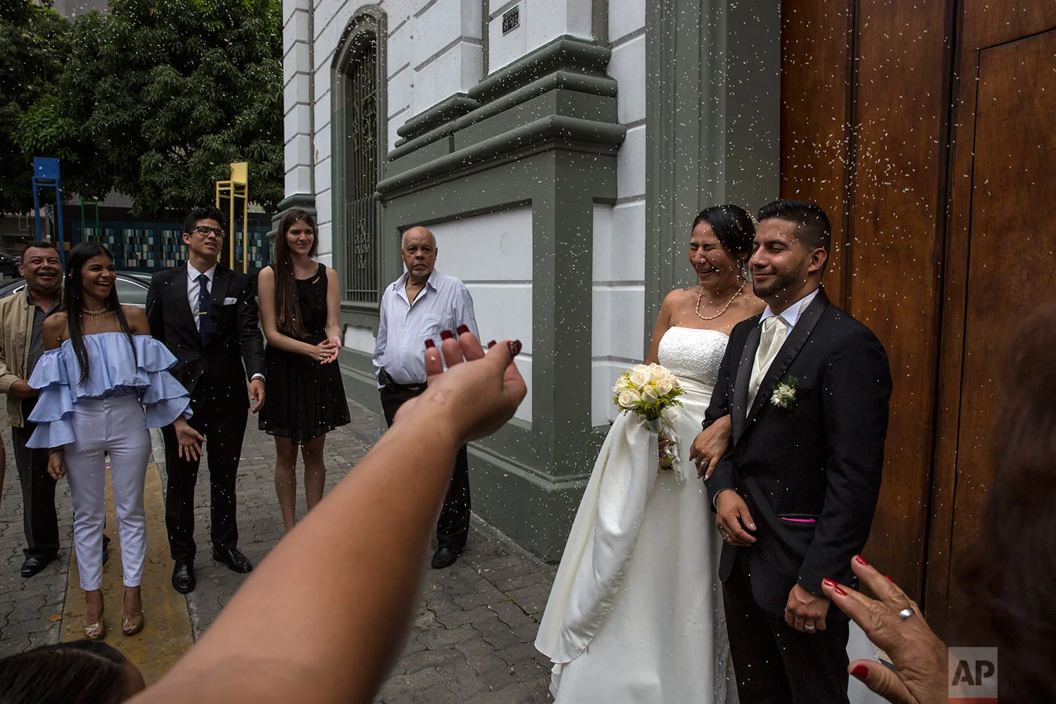 Wedding guests throw rice at Nalitza Perez, 44, and her groom Jason Cifuentes, 26, outside a church in Caracas, Venezuela, Saturday, Oct. 21, 2017. (AP Photo/Rodrigo Abd)