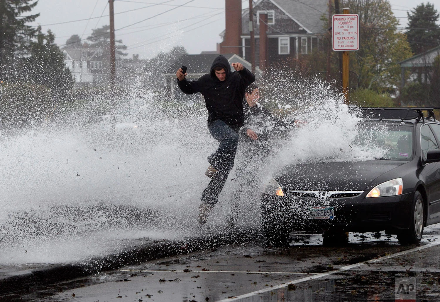 Caleb Lavoie, 17, of Dayton, Maine, front, and Curtis Huard, 16, of Arundel, Maine, leap out of the way as a large wave crashes over a seawall on the Atlantic Ocean during the early stages of Hurricane Sandy, Monday, Oct. 29, 2012, in Kennebunk, Maine. (AP Photo/Robert F. Bukaty)