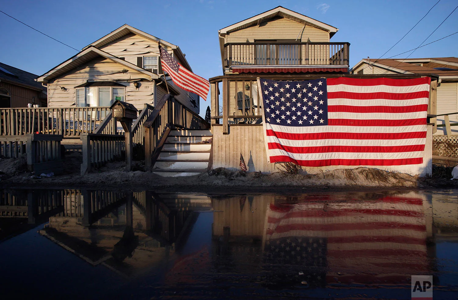 United States flags are displayed on flood-damaged homes in the Breezy Point section of Queens, N.Y., Wednesday, Nov. 28, 2012. (AP Photo/Mark Lennihan)