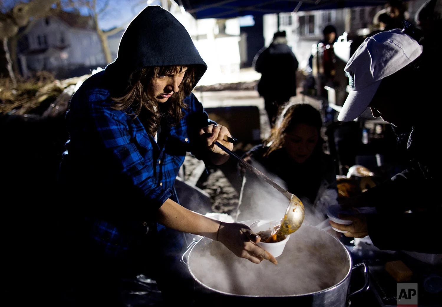 Ariel Nadelberg of the Brooklyn borough of New York pours hot soup in a cup at a parking lot that has become make shift place where those in need can get food and clothing in a Rockaway neighborhood of the borough of Queens, New York, Monday, Nov. 5, 2012, as efforts to bring goods and services to people goes on in the wake of Superstorm Sandy. Many volunteers have shown up on their own to try to lend a hand any way they can. (AP Photo/Craig Ruttle)