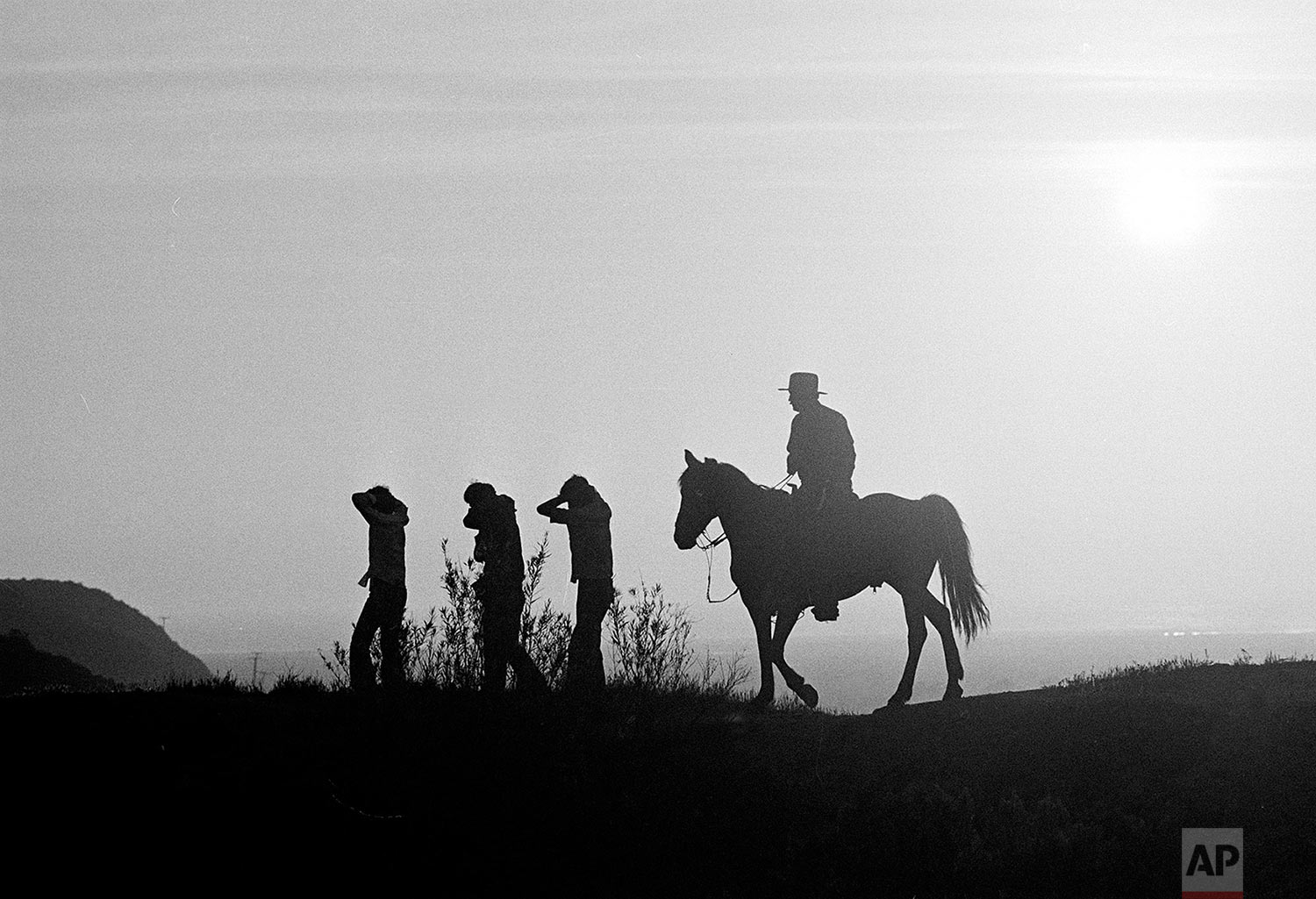  In this Aug. 18, 1981, photo taken by Associated Press photographer Lennox McLendon, shows U.S. Border Patrol officer Ed Pyeatt, on horseback, leading a group of immigrants who crossed the border without legal permission, down the hillside toward wa