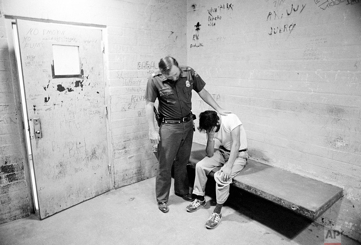  U.S. Border Patrol officer Ed Pyeatt consoles an unidentified illegal immigrant sitting in a cell at Chula Vista station, a border town to Mexico, August 18, 1981. "With a government that doesn't care for them, indecent living conditions and poverty
