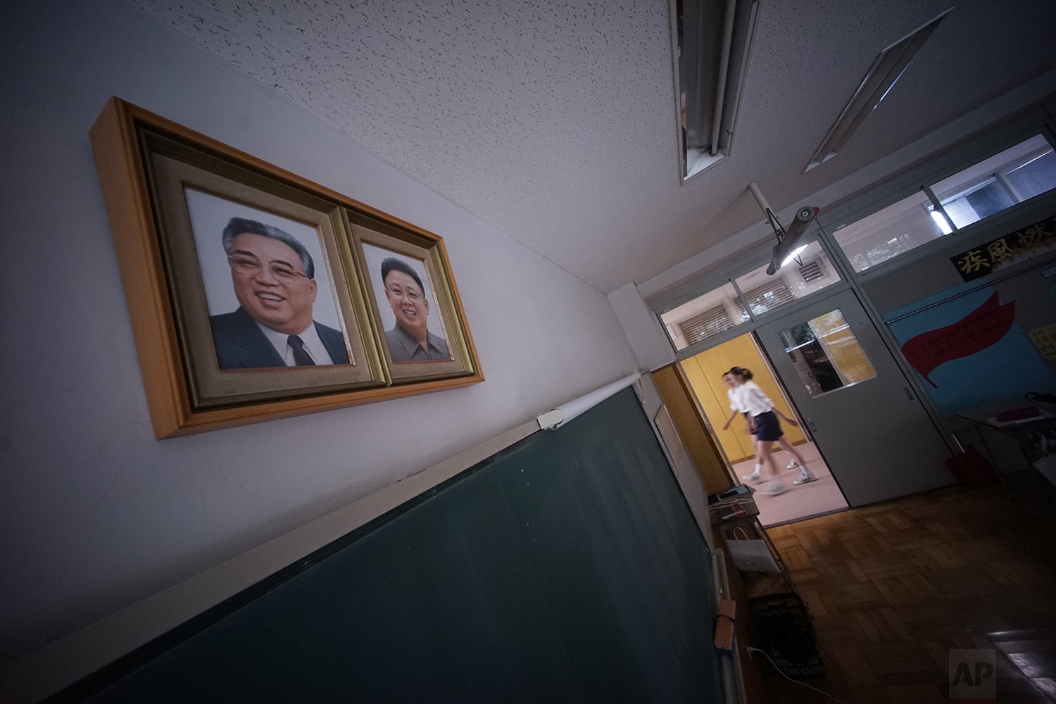  In this Sept. 26, 2017, photo, students walk by a classroom where the portraits of the late North Korean leaders Kim Il Sung and Kim Jong Il hang on the wall at a Tokyo Korean junior and senior high school in Tokyo.  (AP Photo/Eugene Hoshiko) 