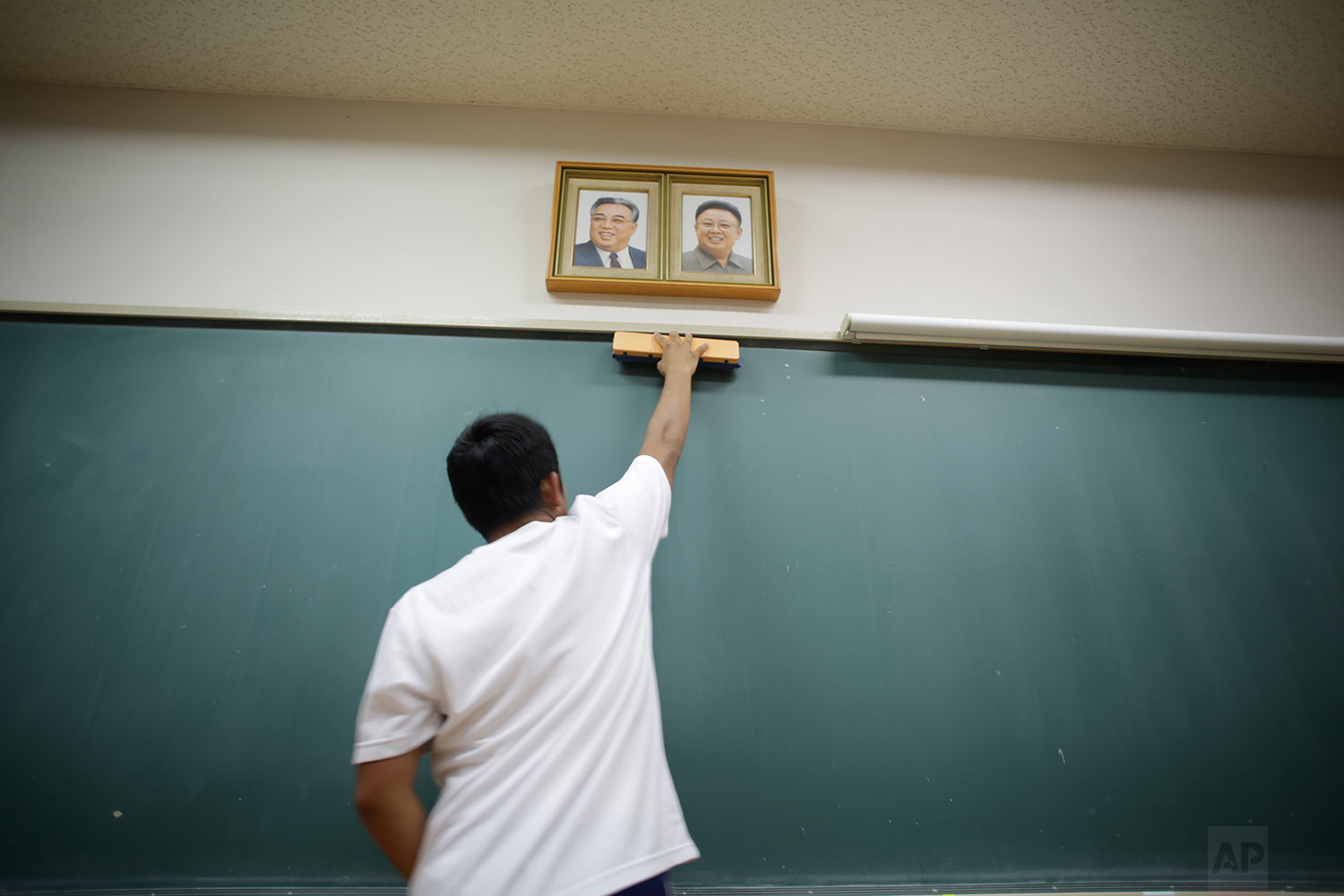  In this Sept. 26, 2017, photo, a student cleans the blackboard under the portraits of the late North Korean leaders Kim Il Sung and Kim Jong Il hanging in classroom at a Korean high school in Tokyo.  (AP Photo/Eugene Hoshiko) 