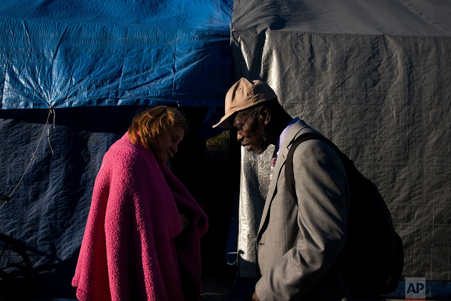 Two homeless people, Tammy Stephen, 54, left, and Bennie Koffa, 66, walk past each other at Camp Second Chance, a city-sanctioned homeless encampment, Tuesday, Sept. 26, 2017, in Seattle. Against the backdrop of its booming economy, the West Coast is experiencing another type of boom_a massive surge in homeless people living on the streets that in many places is beginning to overwhelm the ability of local governments to deal with it. (AP Photo/Jae C. Hong)